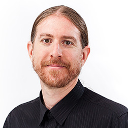 Portrait of a man with long hair and beard wearing a black shirt