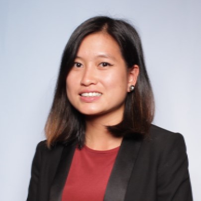 Professional headshot of woman in black blazer and maroon top smiling