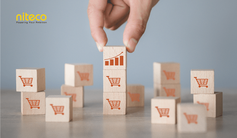 Hand stacking wooden blocks with shopping carts and growth chart symbolizing sales growth