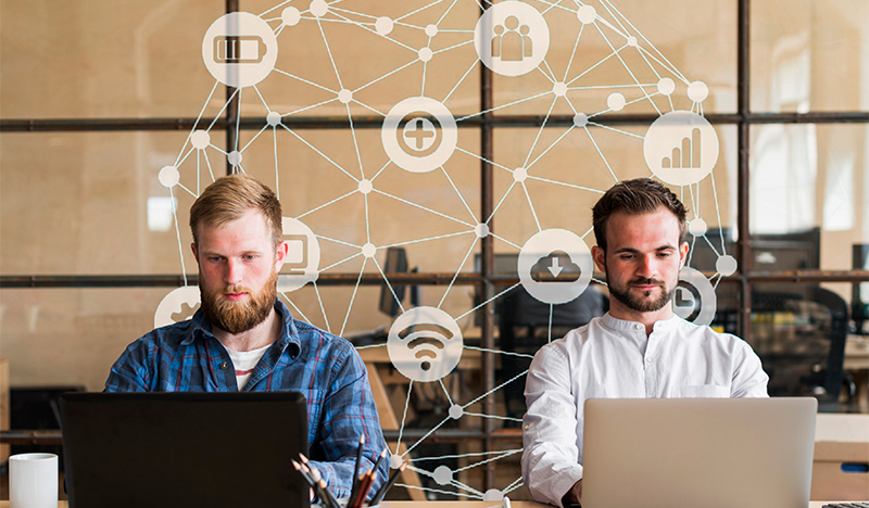 Two professionals working on laptops with digital network and data icons
