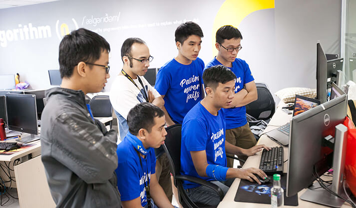 Team of programmers collaborating around computer screens in an office