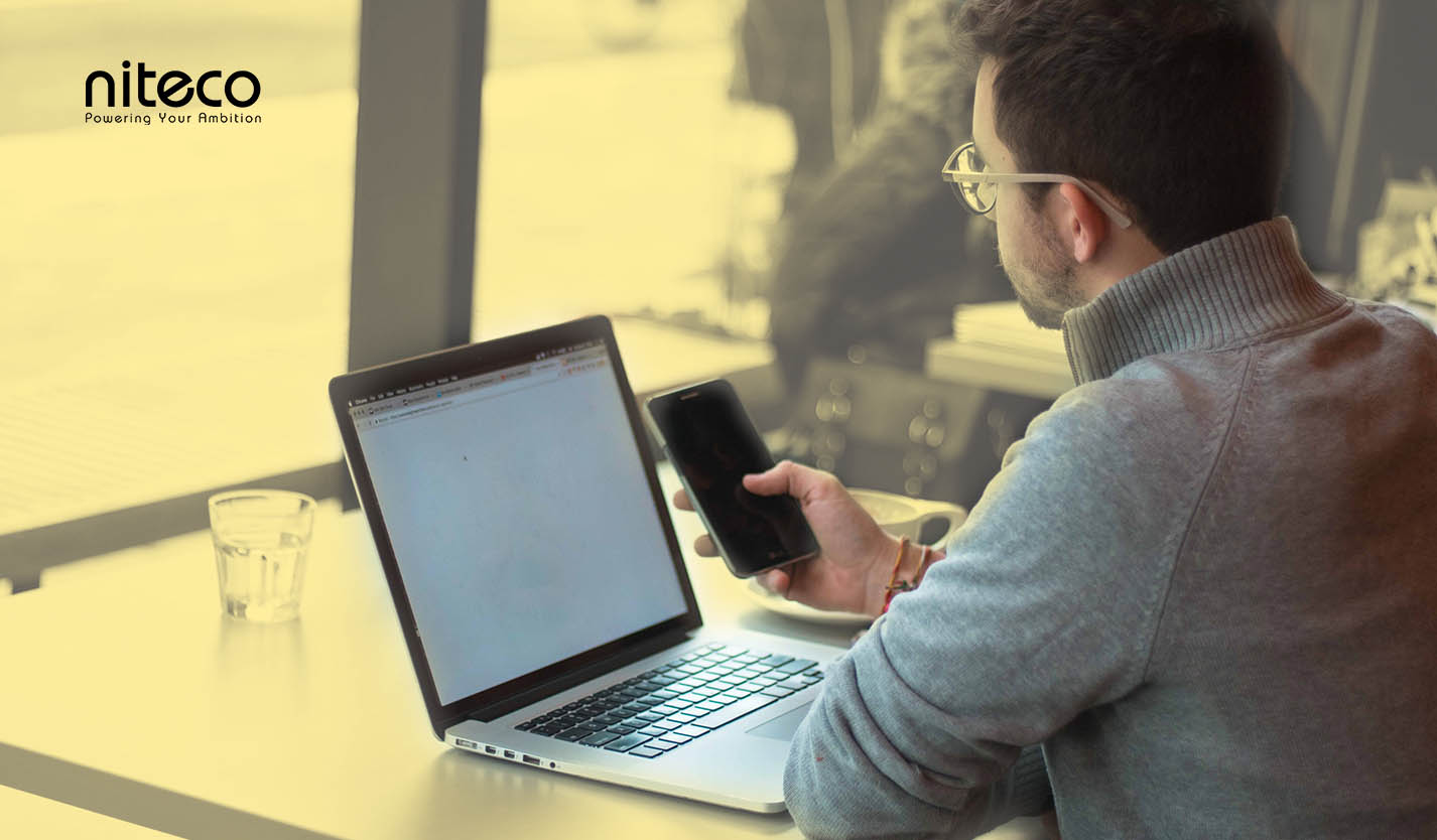 Man using smartphone and laptop for productivity with Niteco branding