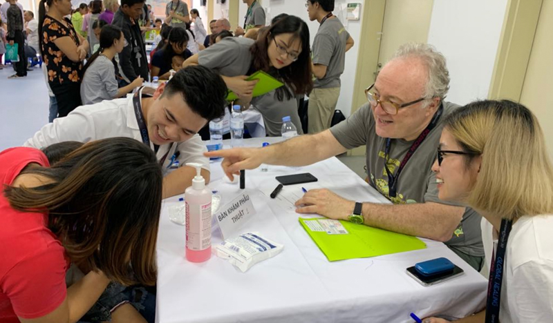 Volunteers assisting attendees at medical check-up station with masks and supplies