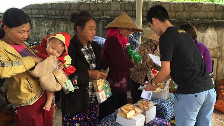 Vietnamese people receiving free food and supplies at a community aid event